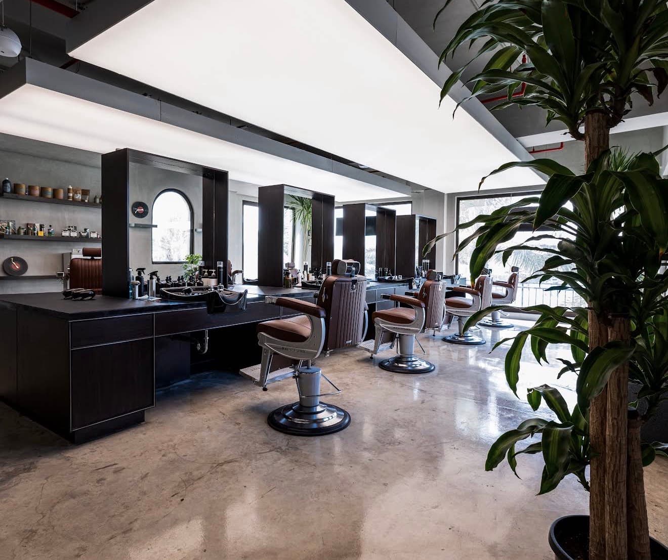 The Chops Barbers cutting floor in daylight: a row of leather barber chairs facing black mirror stations, on polished concrete