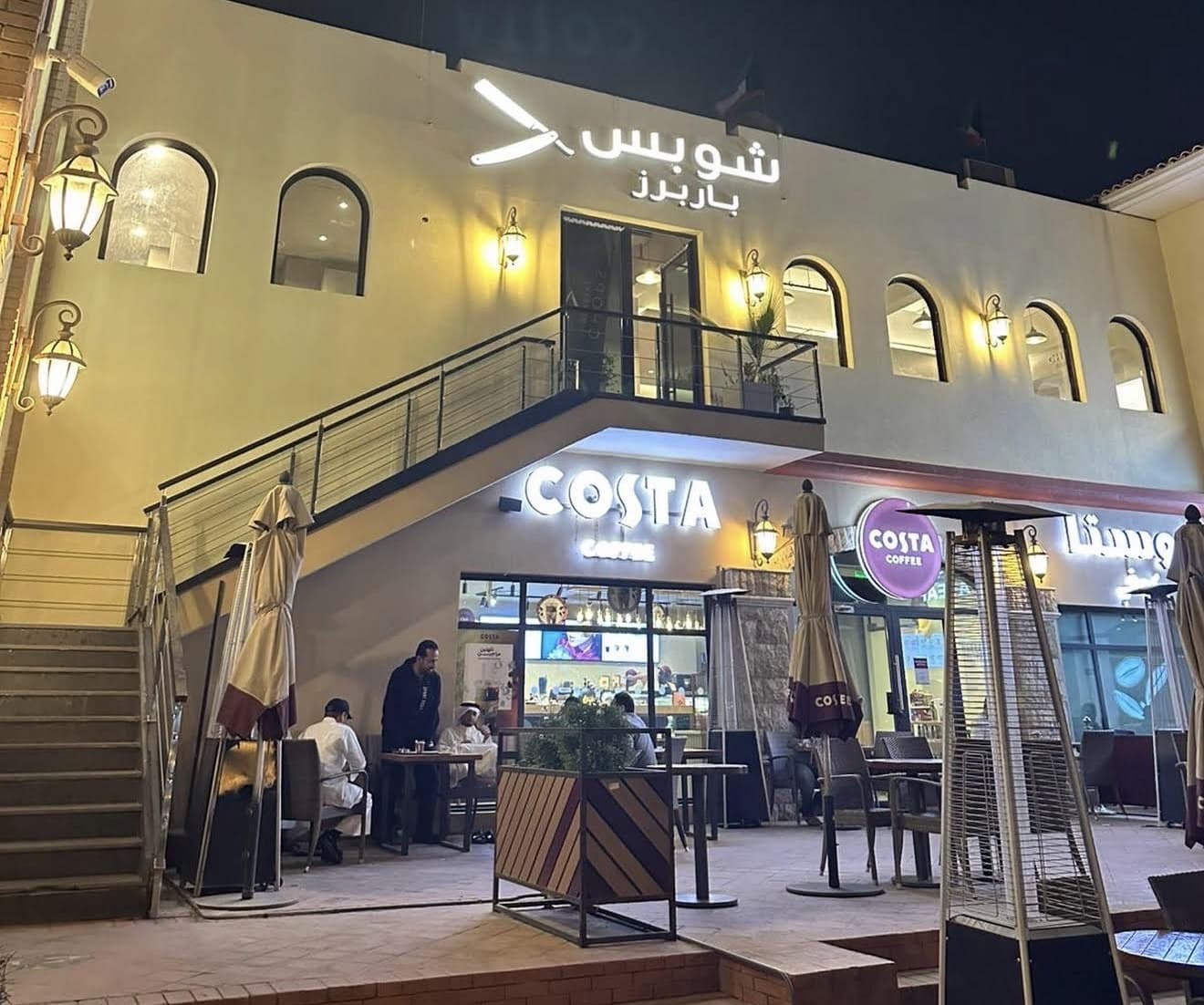 The lit Chops Barbers sign above the shopfront in Salwa at night
